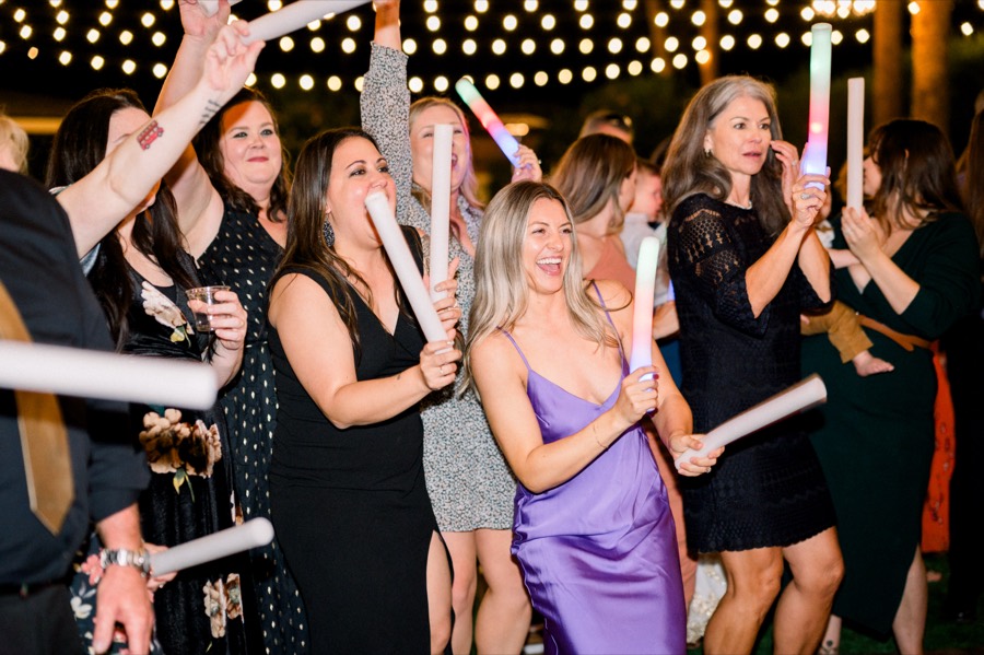 Wedding guests celebrating with glow sticks under string lights at Gather Estate in Mesa with DJ Take2